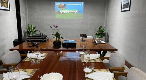 a long wooden table with chairs and wine glasses at Asian Koh Kong Hotel in Koh Kong