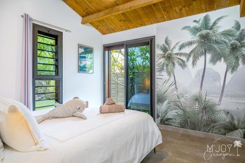 a bedroom with a white bed with teddy bears on it at KAZ BALEN***** Villa 10 pers à St-Leu in Le Portail