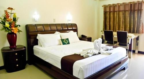 a bedroom with two beds and a vase with flowers at The Premiere Business Hotel in Kalibo