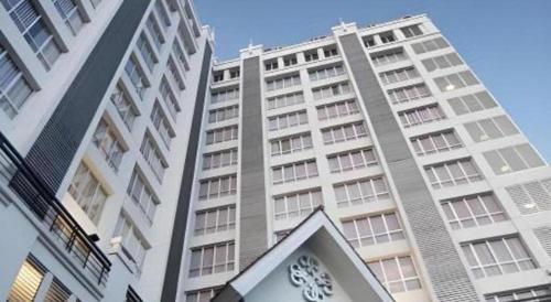 a tall building with a clock in front of it at Grand Darmo Suite by AMITHYA in Surabaya