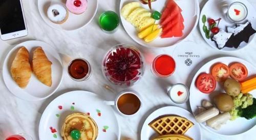 a white table with plates of food on it at Grand Darmo Suite by AMITHYA in Surabaya