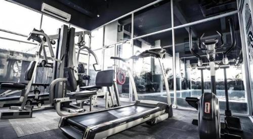a gym with a treadmill and ellipticals in a room at Grand Darmo Suite by AMITHYA in Surabaya