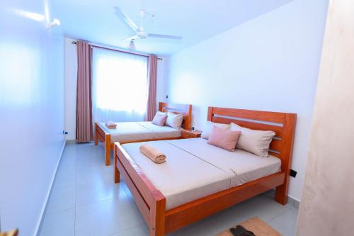 a bedroom with two beds and a window at Casacylen in Mombasa