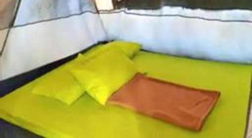 a green and white bed with yellow pillows on it at Herman Lantang Camp in Bogor