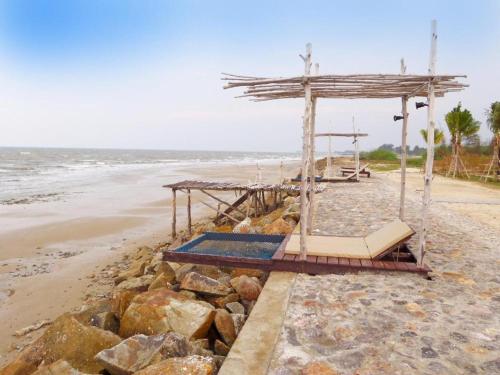 a bed on a beach next to the ocean at Red Z The Ocean in Phetchaburi