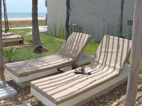 two lounge chairs sitting in a yard with the beach at Red Z The Ocean in Phetchaburi