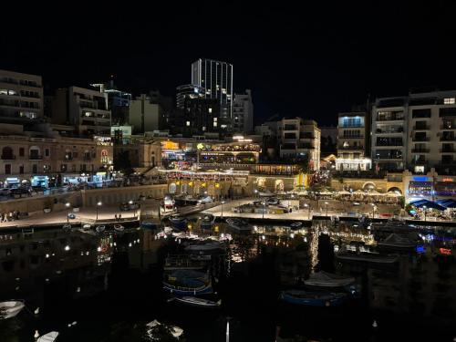 a city at night with boats in a harbor at Bay View Apartments in St Julian's