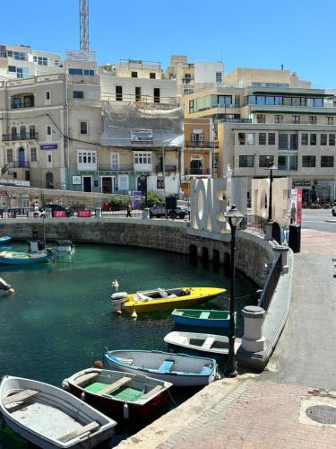 a group of boats docked in a river with buildings at Bay View Apartments in St Julian's