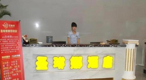 a woman standing behind a counter in a kitchen at Sheng Lin Na Hotel Minzhi Branch in Shenzhen