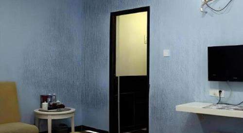 a room with a blue wall with a door and a television at Sheng Lin Na Hotel Minzhi Branch in Shenzhen