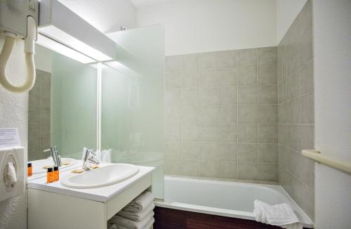 a white bathroom with a sink and a bath tub at Occitania Centre Toulouse Matabiau in Toulouse
