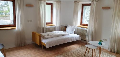 a small bedroom with a bed and two windows at Gutshof zum Wurzgarten in Hainbach