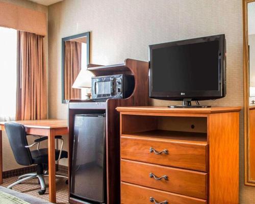 a hotel room with a television on a dresser with a desk at Quality Inn in Sidney