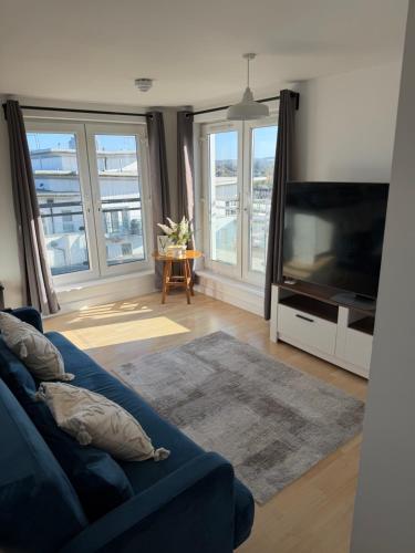 a living room with a blue couch and a flat screen tv at Basingstoke Train Station Short Stay in Basingstoke
