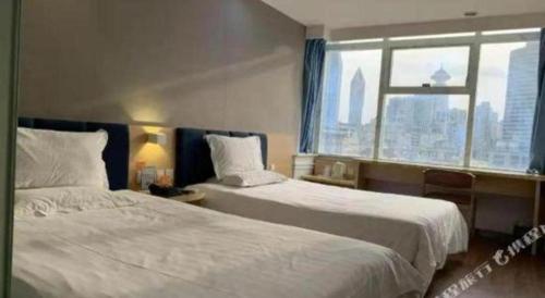 a hotel room with two beds and a window at 7 Days Inn Shanghai Minhang Dongchuan Road Jiaotong University in Shanghai