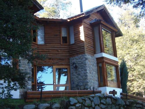 Cabaña de madera con pared de piedra y ventanas en La Torre de la Cascada, en Villa La Angostura