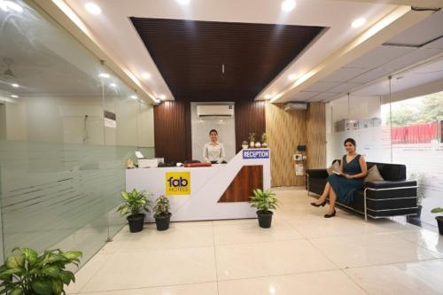 Dos mujeres sentadas en un mostrador de recepción en un vestíbulo. en Via Palm Paradise, en Noida