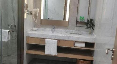 a bathroom with a sink and a mirror and towels at Dong Cheng Hotel in Shunde