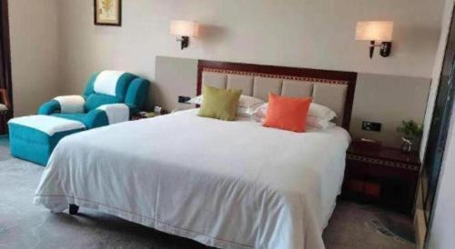 a bedroom with a large white bed and a blue chair at Dong Cheng Hotel in Shunde