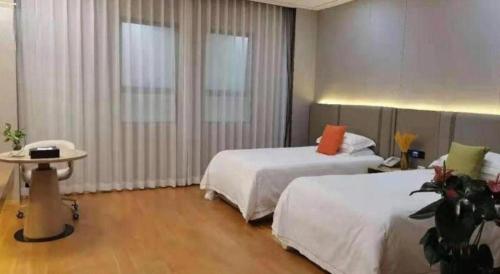 a hotel room with two beds and a table at Dong Cheng Hotel in Shunde