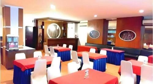 a restaurant with red and white tables and white chairs at Alexander Hotel Tegal in Tegal
