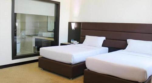 two beds in a hotel room with a mirror at The BCC Hotel & Residence in Nagoya