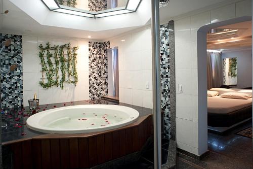 a bathroom with a bath tub and a bedroom at Hotel Itaoka (Adults Only) in Rio de Janeiro