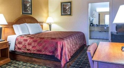 a hotel room with a bed with a red blanket at Econo Lodge Dalton West in Dalton
