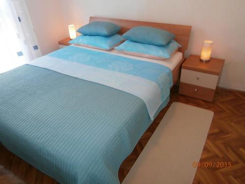 sypialnia z dużym łóżkiem z niebieskimi poduszkami w obiekcie Apartman Lovran w mieście Lovran