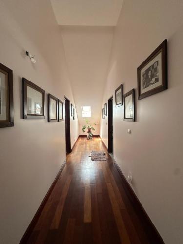 a hallway with white walls and wooden floors and framed pictures at Casa Beija flor quarto Ortencias in Mogofores