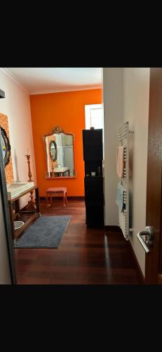 a living room with an orange wall and a mirror at Casa Beija flor quarto Ortencias in Mogofores