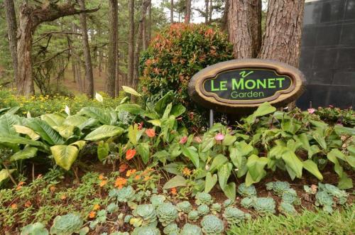 a sign in a garden with flowers and plants at Le Monet Hotel in Baguio