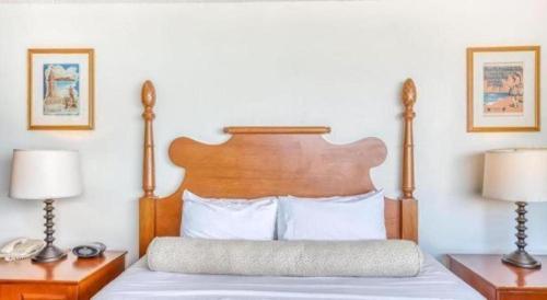 a bedroom with a bed with a wooden headboard and two lamps at Marina Tower Waikiki in Honolulu