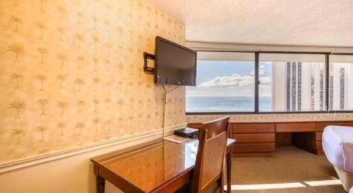 a hotel room with a desk and a bed and a television at Marina Tower Waikiki in Honolulu