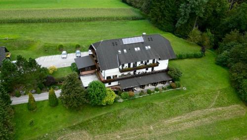 a large house with a black roof on a green field at Nature Hotel Lukanc in Bled