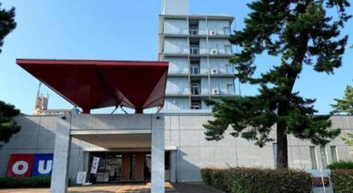 a building with a red roof in front of a building at Ou Hotel in Yonago