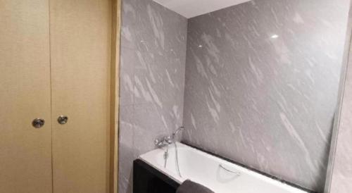 a bathroom with a gray wall and a bath tub at Brits Hotel Karawang in Karawang