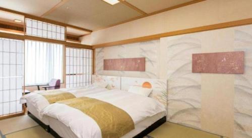 a bedroom with a large bed in a room with windows at Centurion Hotel Technoport Fukui- Artificial Radium Hot Spring in Sakai