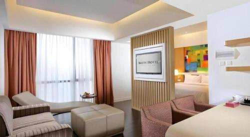 a hotel room with a bed and a tv on a wall at Brits Hotel Karawang in Karawang