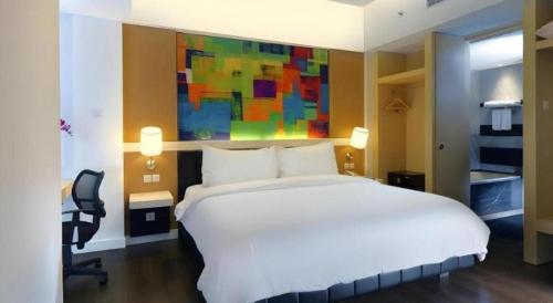 a bedroom with a large white bed and a desk at Brits Hotel Karawang in Karawang