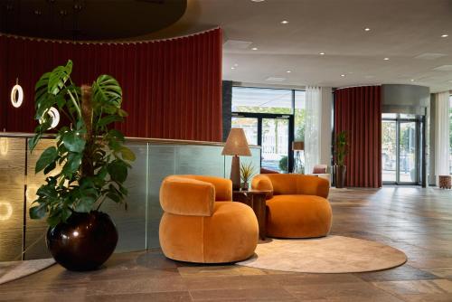 a lobby with orange chairs and a potted plant at Haven Hotel Rotterdam, Curio Collection by Hilton in Rotterdam