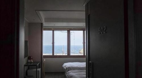 a bedroom with a view of the ocean from a window at Check Inn Hotel in Jeju