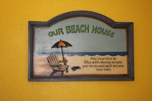 a picture of a beach house with a chair and an umbrella at Barefoot Bay Resort Motel in Clearwater Beach