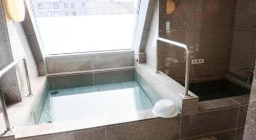 a bathroom with a bath tub with a window at Hotel Shimbashi Sambankan in Tokyo