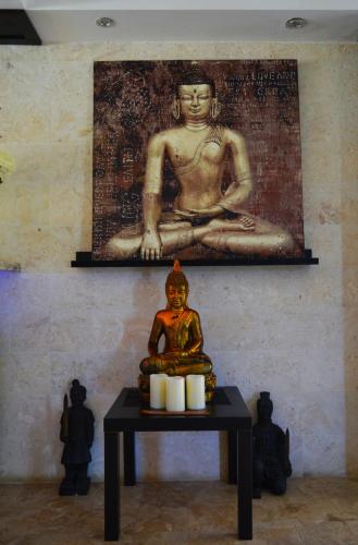 a statue on a table in front of a painting of a buddha at Savoy Hotel Boutique in Las Terrenas