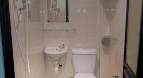a white bathroom with a toilet and a sink at Power Hotel in Georgetown