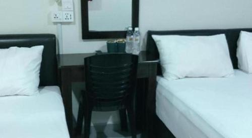 a bedroom with a desk and a chair between two beds at Power Hotel in Georgetown