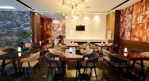 a restaurant with wooden tables and chairs and a chandelier at Zmax Changzhi Bayi Square in Changzhi