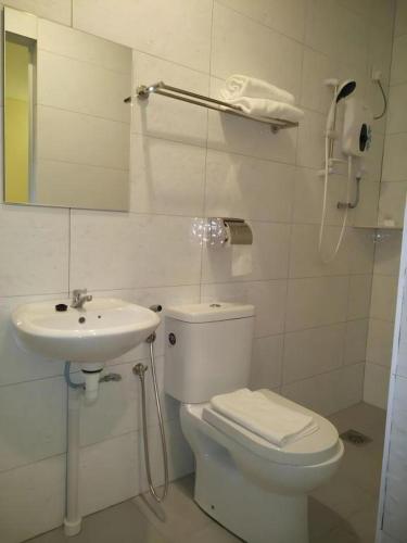 a white bathroom with a toilet and a sink at Hotel Pangkor Mutiara in Pangkor