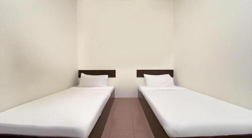 two beds in a room with white walls at SPOT ON 91178 Motel Impian in Seri Manjung